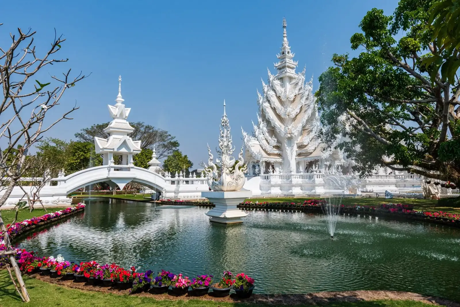 Temple garden with a fountain pond, flowerbeds and a white bridge
