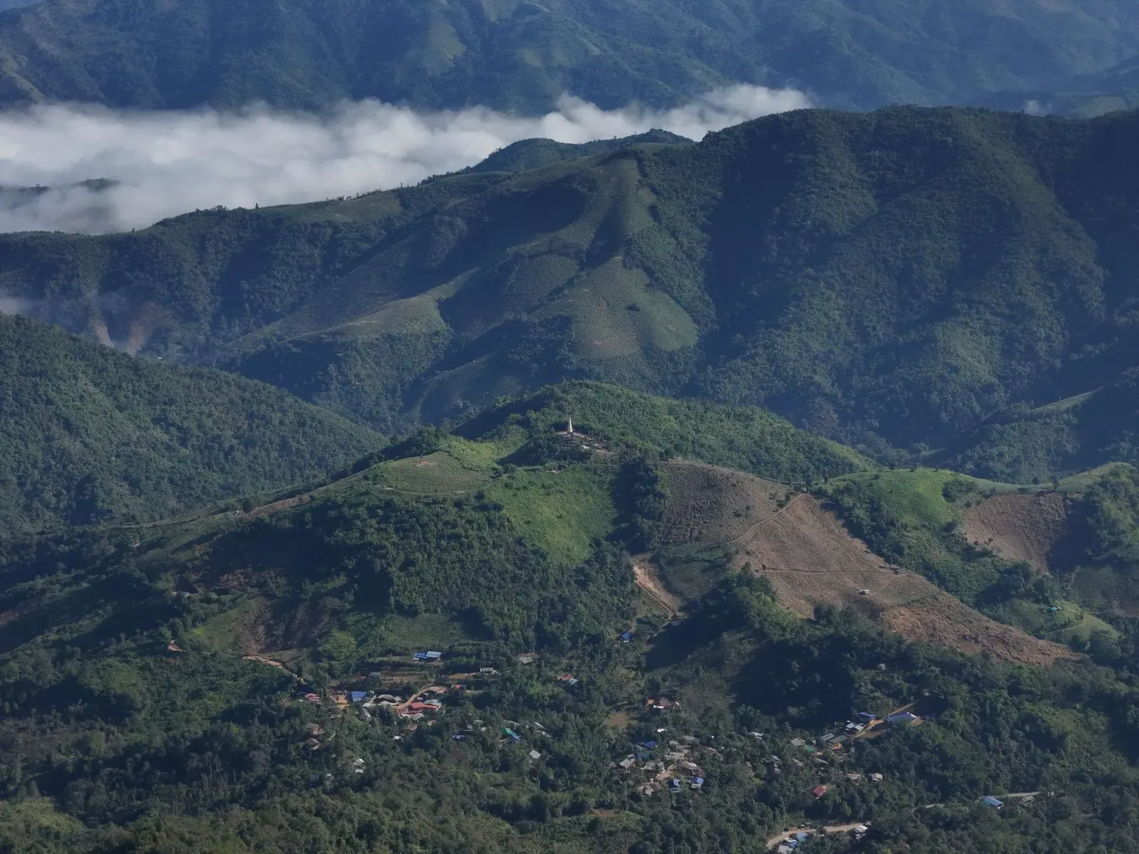 Aerial view of forested mountains and a valley village in Chiang Mai