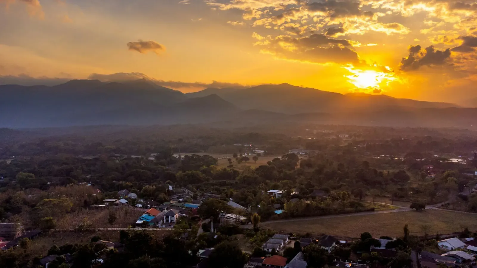 Aerial view of a valley with houses at golden hour in Mae Rim