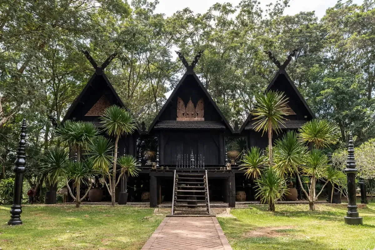 Black wooden halls among palm trees at Baan Dam