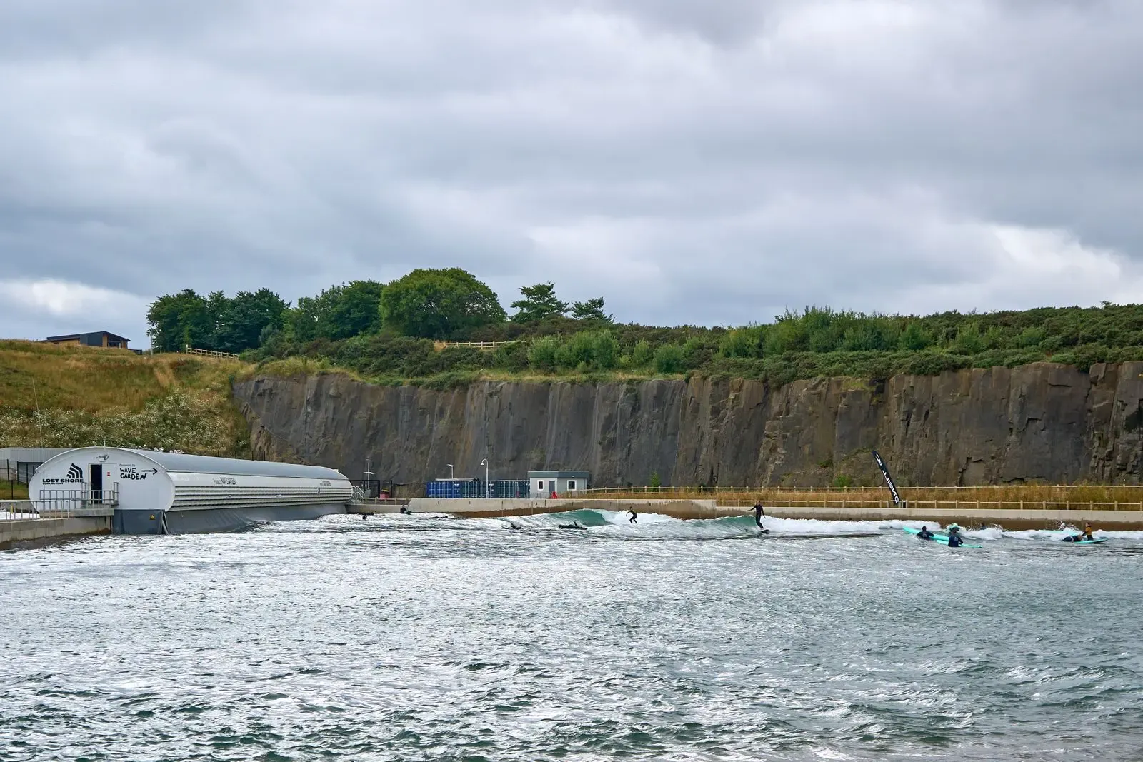 An artificial surf wave pool below a quarry cliff